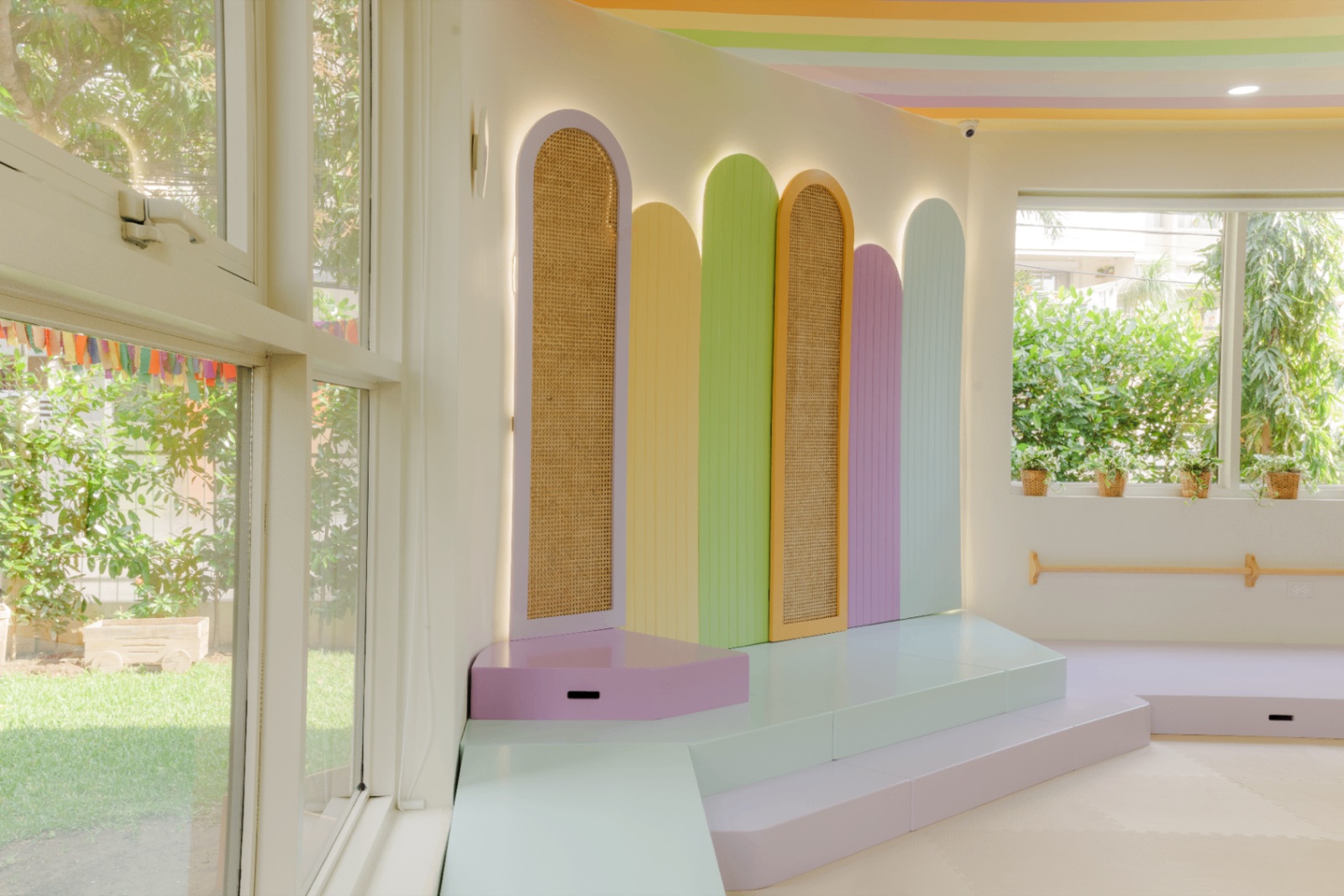 Espacio infantil de neuroarquitectura con arcos pastel, rattan y luz natural