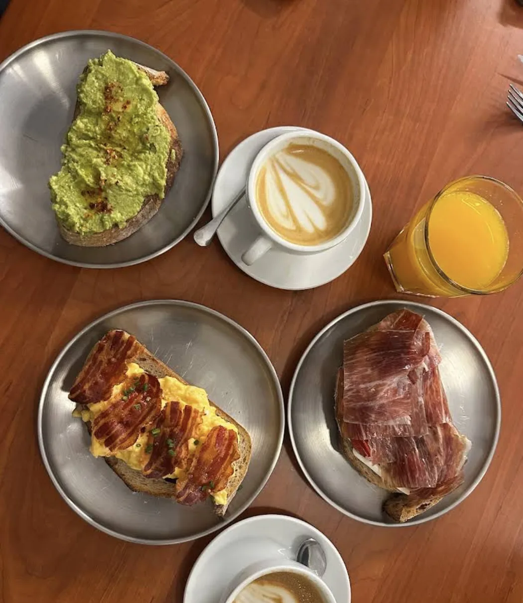 Tostada de aguacate, huevos con bacon, bocadillo de jamón ibérico, café y zumo de naranja