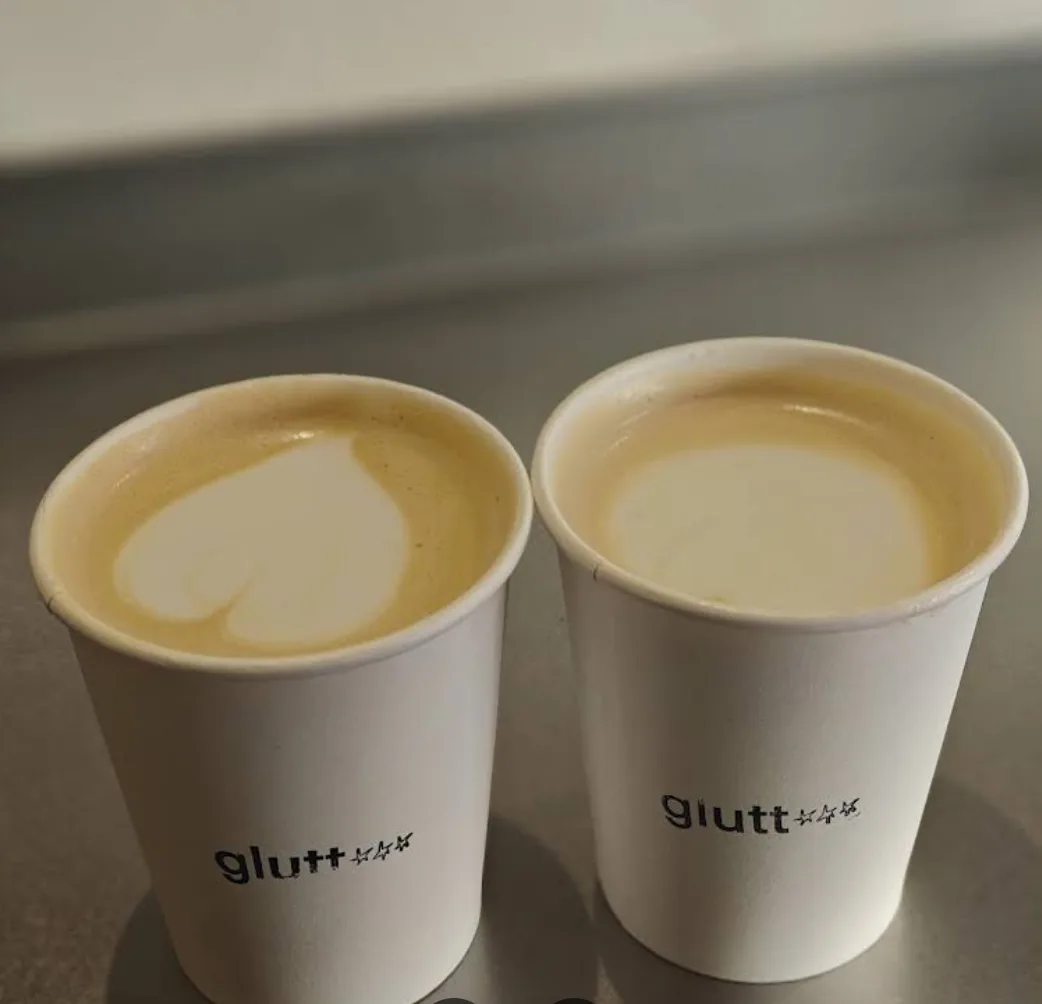 Dos cafés para llevar en vasos con el logo de Gluttoni