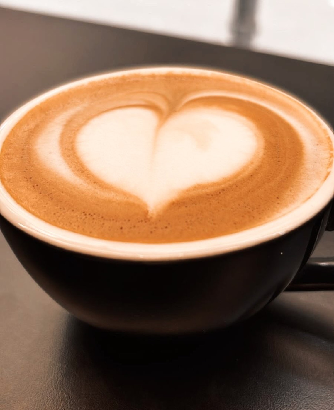 Latte art en forma de corazón sobre taza negra