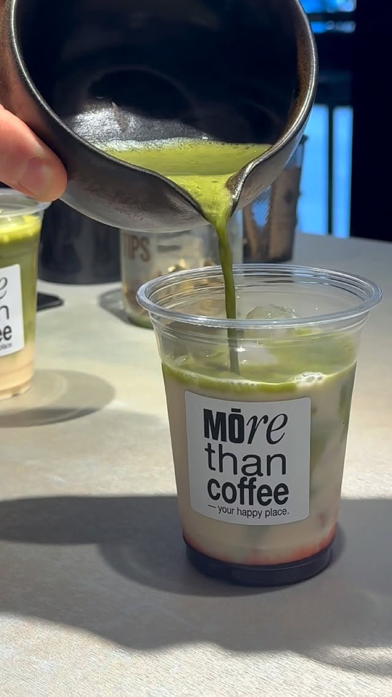 Matcha recién batido cayendo sobre un vaso de leche fría con hielo