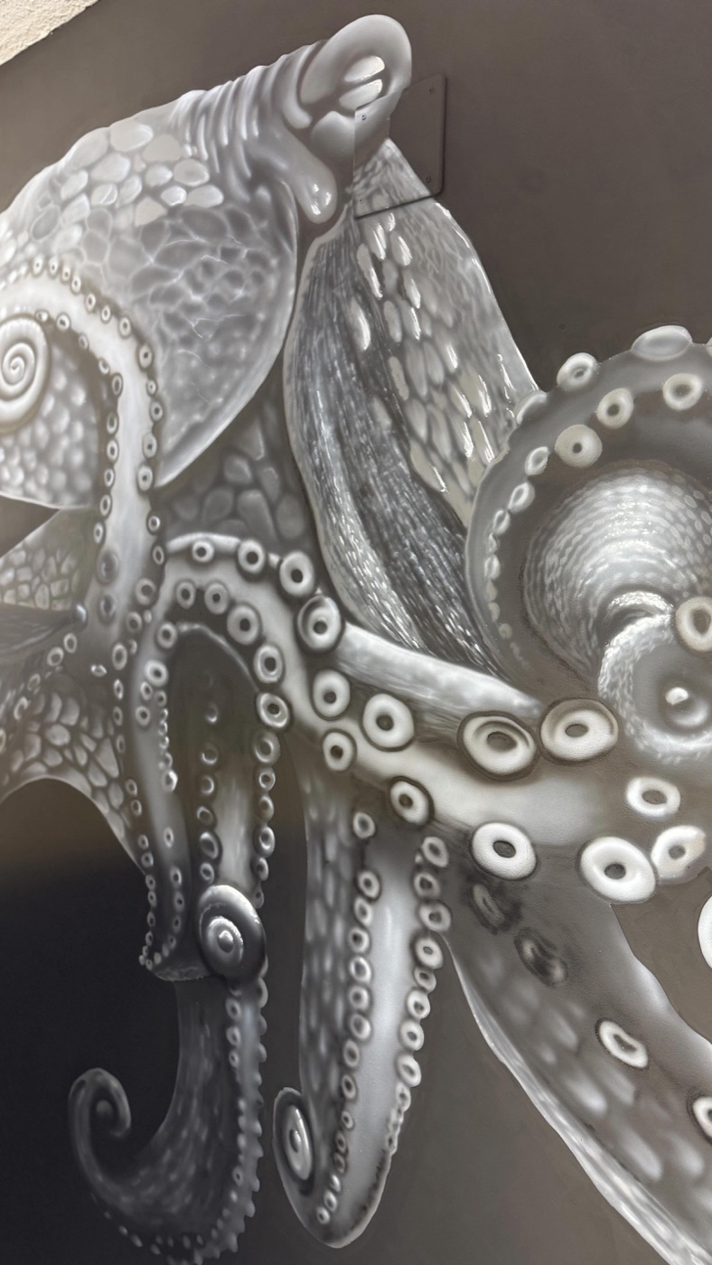 Mural de un pulpo pintado a aerógrafo en blanco y negro en la pared del local