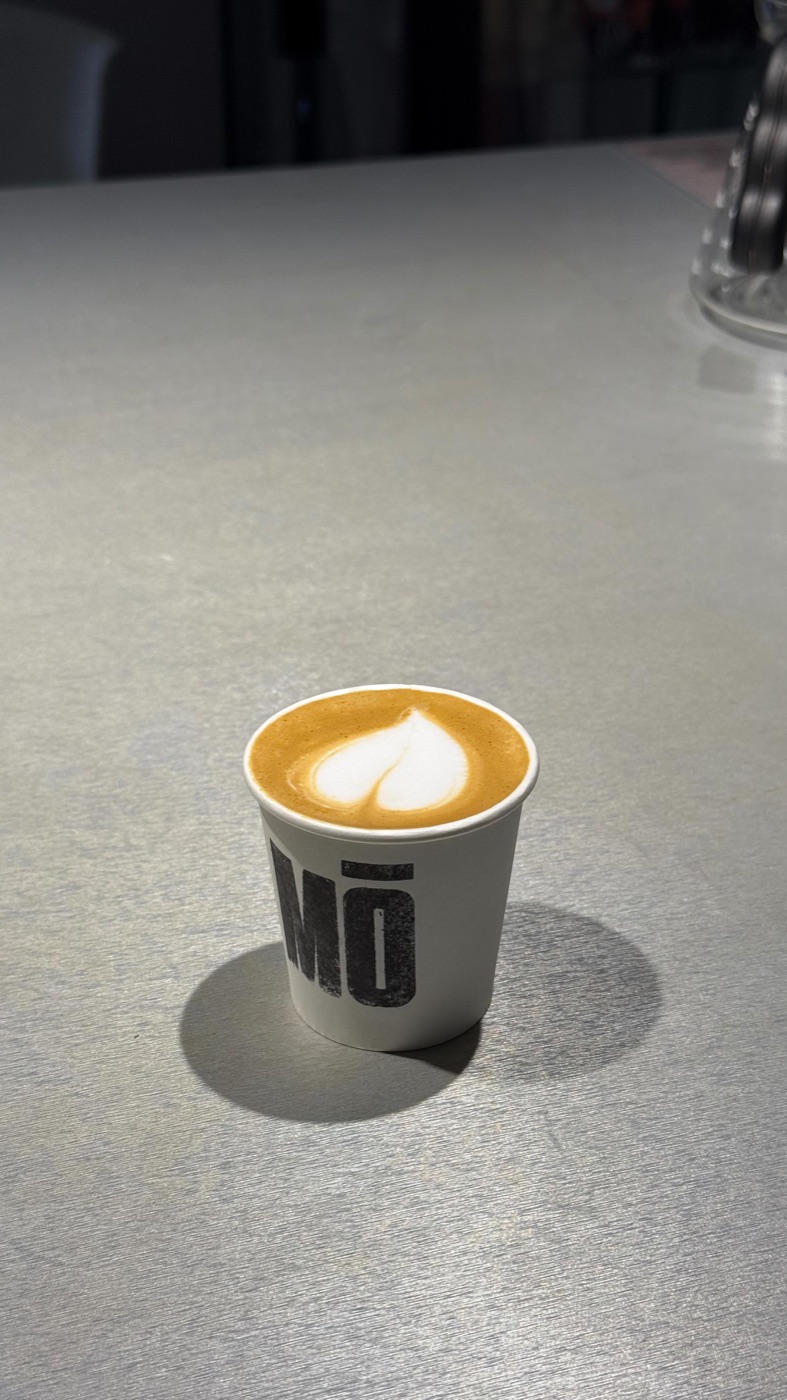 Flat white en vaso para llevar con el logo MŌ