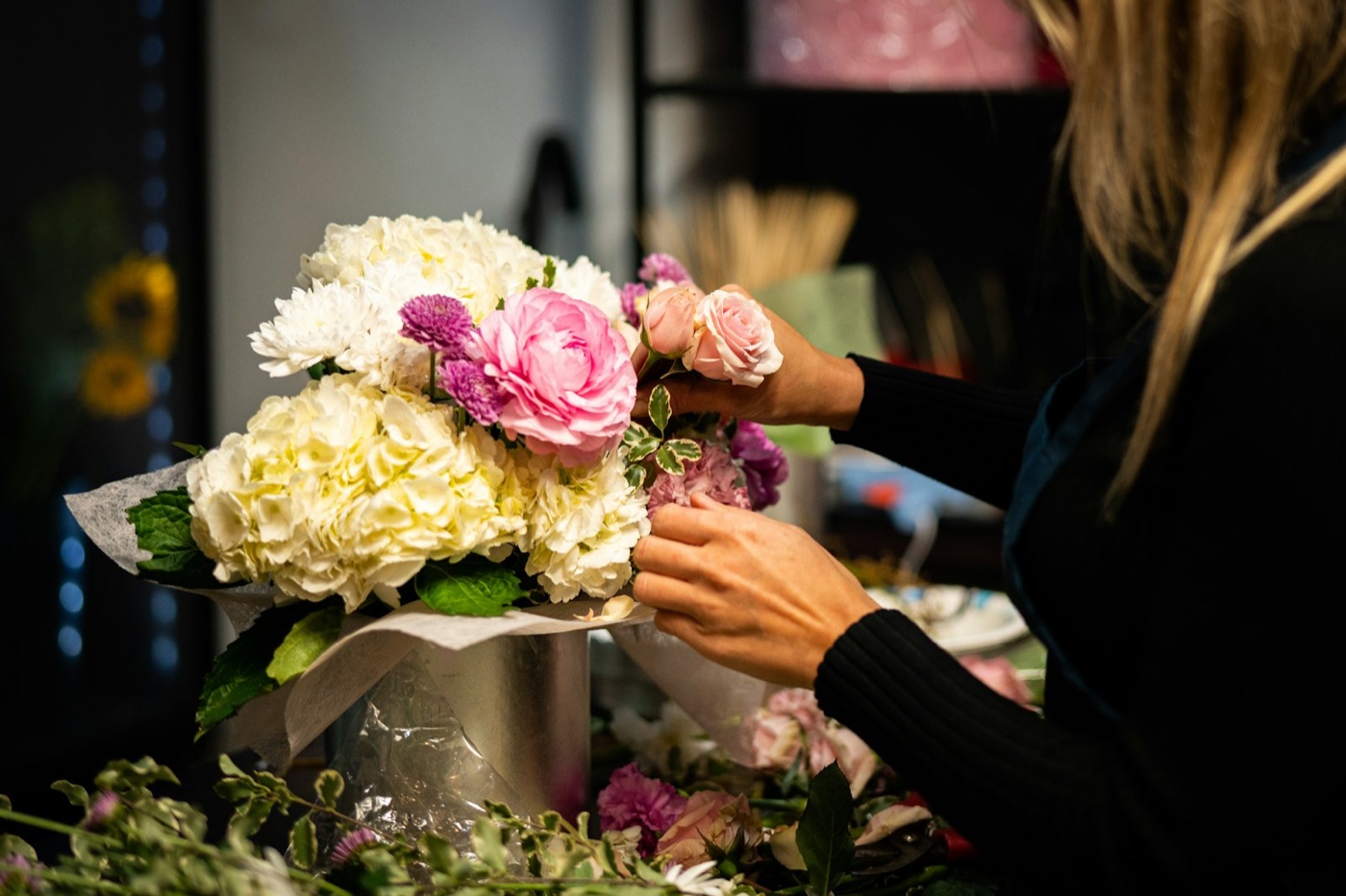 Manos preparando un arreglo floral en la floristería